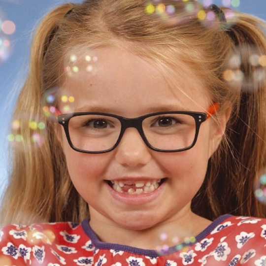 Young girl smiling, wearing glasses